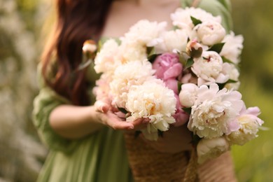 Photo of Beautiful woman with bouquet of peonies in park, closeup
