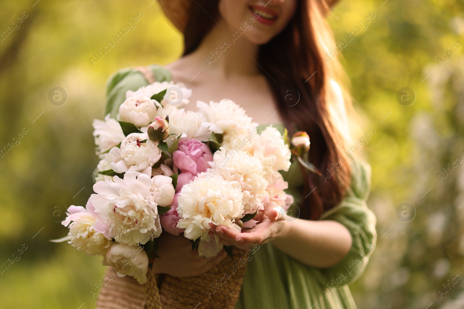 Photo of Beautiful woman with bouquet of peonies in park, closeup