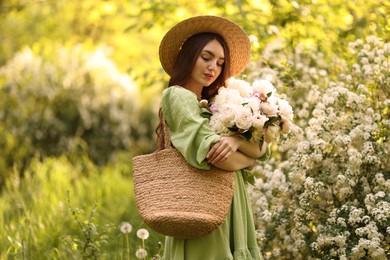 Photo of Beautiful woman with bouquet of peonies in park. Space for text
