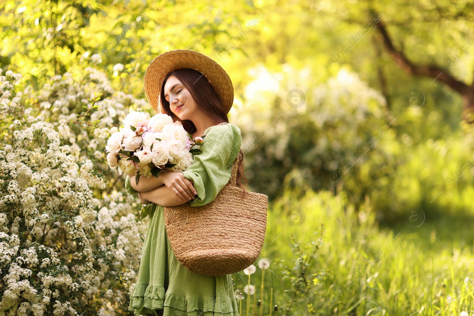 Photo of Beautiful woman with bouquet of peonies in park. Space for text