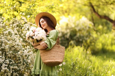 Photo of Beautiful woman with bouquet of peonies in park. Space for text