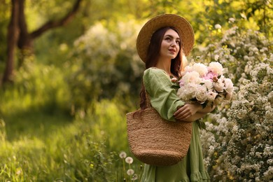 Photo of Beautiful woman with bouquet of peonies in park. Space for text