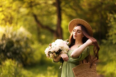 Photo of Beautiful woman with bouquet of peonies in park. Space for text