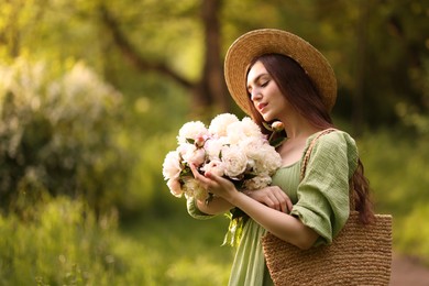 Photo of Beautiful woman with bouquet of peonies in park. Space for text