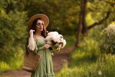 Photo of Beautiful woman with bouquet of peonies in park. Space for text