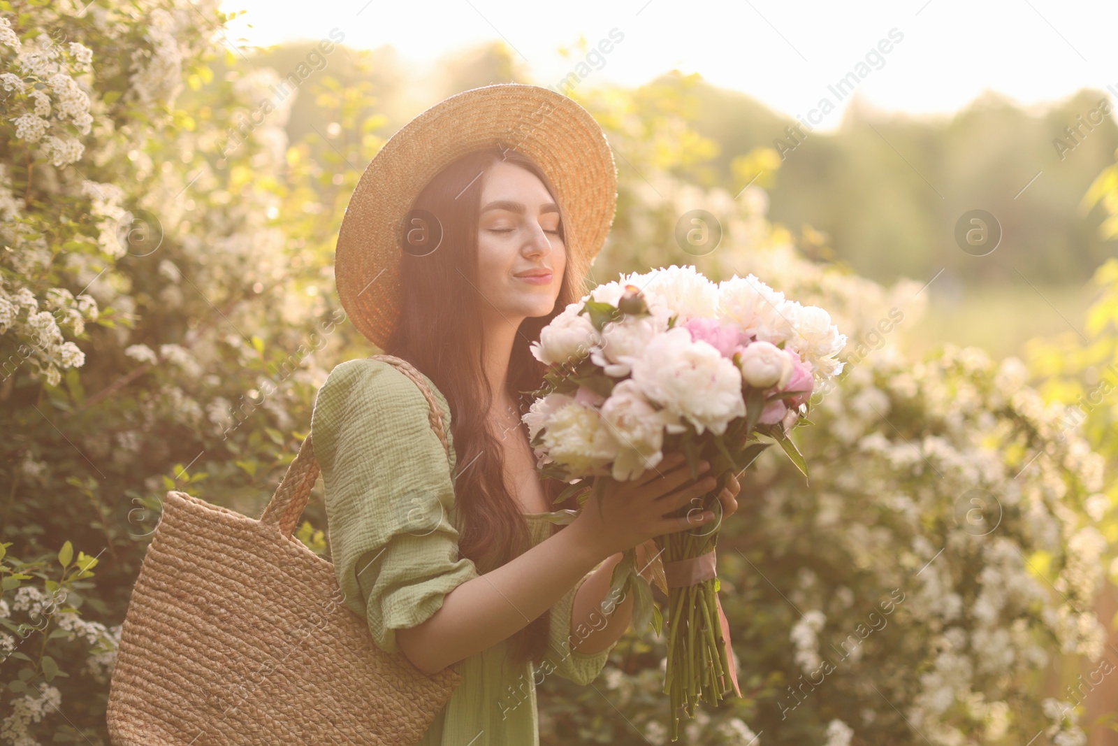 Beautiful woman with bouquet of peonies in park on sunny day Photo of Beautiful woman with bouquet of peonies in park on sunny day