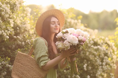 Photo of Beautiful woman with bouquet of peonies in park on sunny day