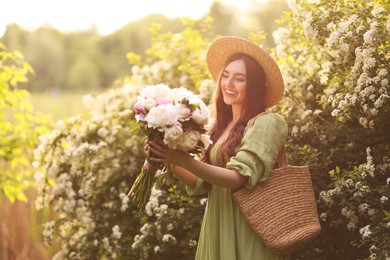 Photo of Beautiful woman with bouquet of peonies in park on sunny day. Space for text