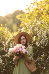 Photo of Beautiful woman with bouquet of peonies in park on sunny day. Space for text
