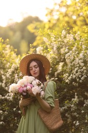 Photo of Beautiful woman with bouquet of peonies in park on sunny day. Space for text