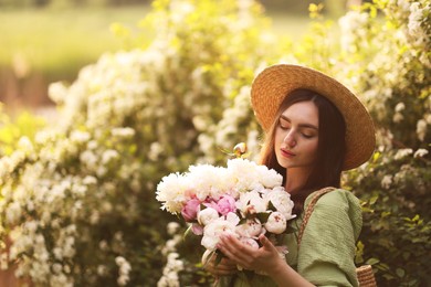 Photo of Beautiful woman with bouquet of peonies in park on sunny day. Space for text