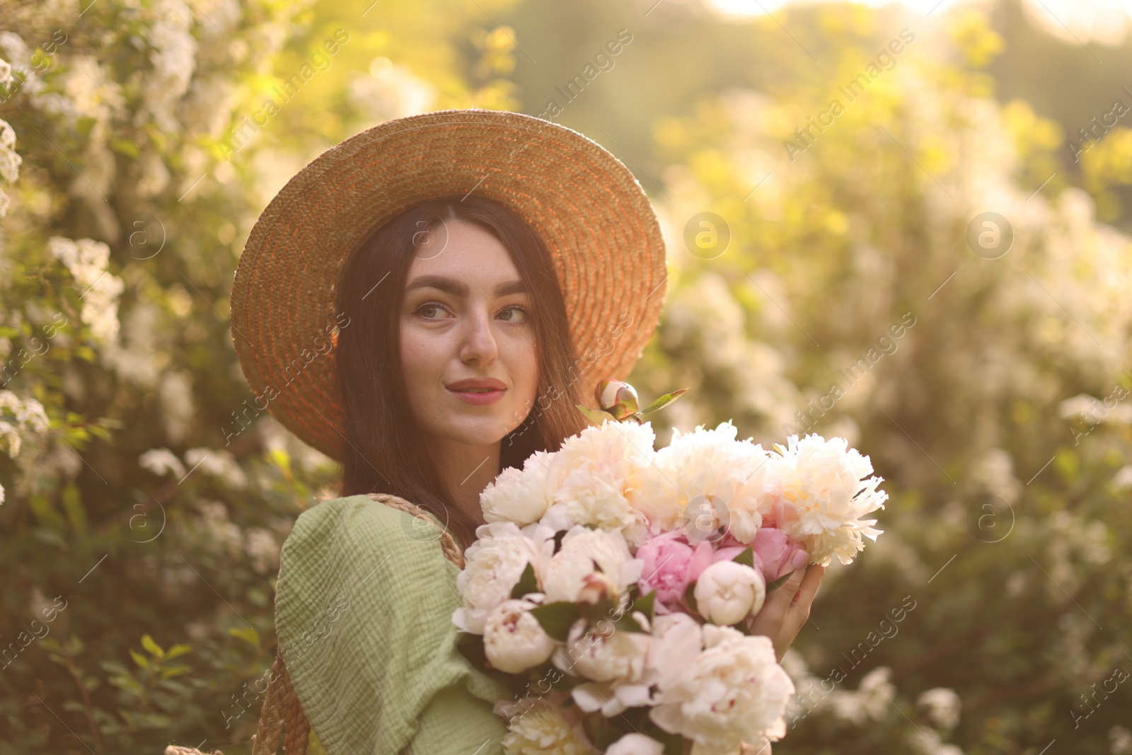 Beautiful woman with bouquet of peonies in park on sunny day Photo of Beautiful woman with bouquet of peonies in park on sunny day