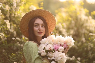 Photo of Beautiful woman with bouquet of peonies in park on sunny day