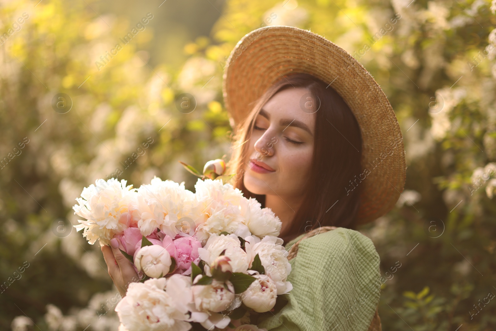 Beautiful woman with bouquet of peonies in park on sunny day Photo of Beautiful woman with bouquet of peonies in park on sunny day