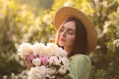 Photo of Beautiful woman with bouquet of peonies in park on sunny day