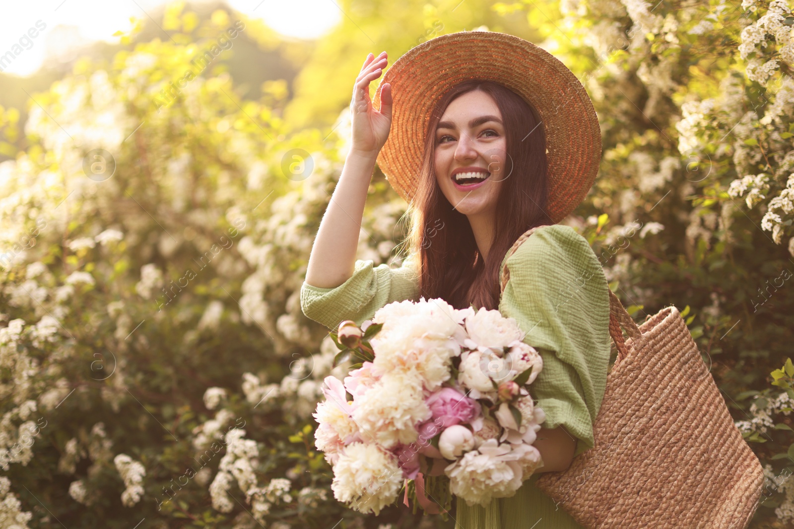 Beautiful woman with bouquet of peonies in park on sunny day Photo of Beautiful woman with bouquet of peonies in park on sunny day