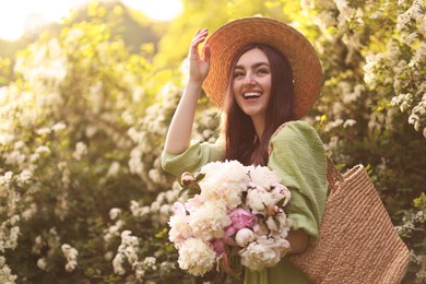Photo of Beautiful woman with bouquet of peonies in park on sunny day