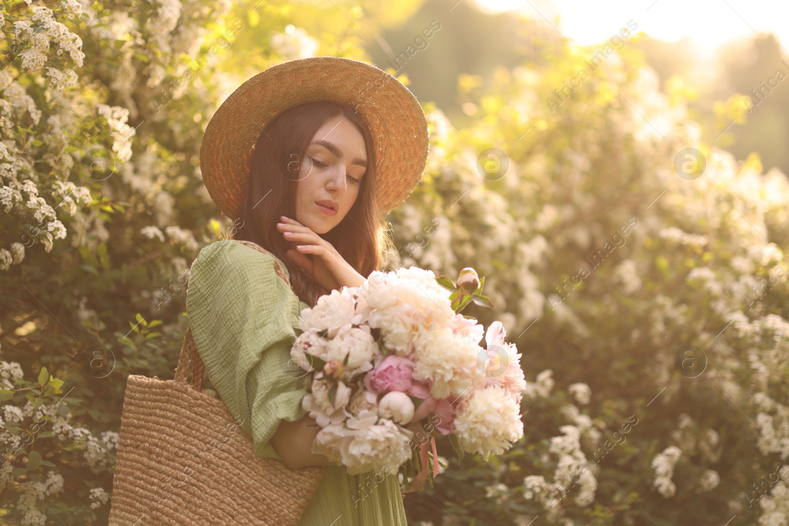 Beautiful woman with bouquet of peonies in park on sunny day Photo of Beautiful woman with bouquet of peonies in park on sunny day