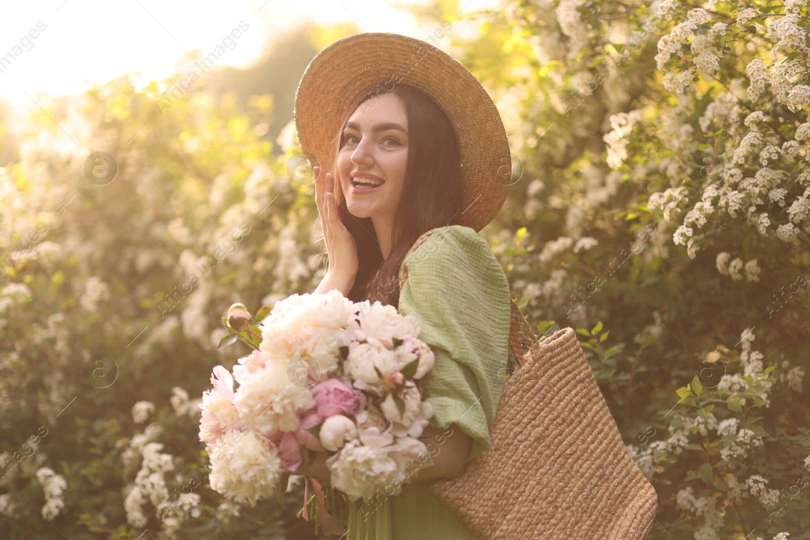 Beautiful woman with bouquet of peonies in park on sunny day Photo of Beautiful woman with bouquet of peonies in park on sunny day