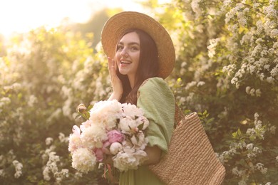 Photo of Beautiful woman with bouquet of peonies in park on sunny day