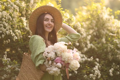 Photo of Beautiful woman with bouquet of peonies in park on sunny day. Space for text