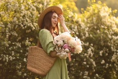 Photo of Beautiful woman with bouquet of peonies in park on sunny day