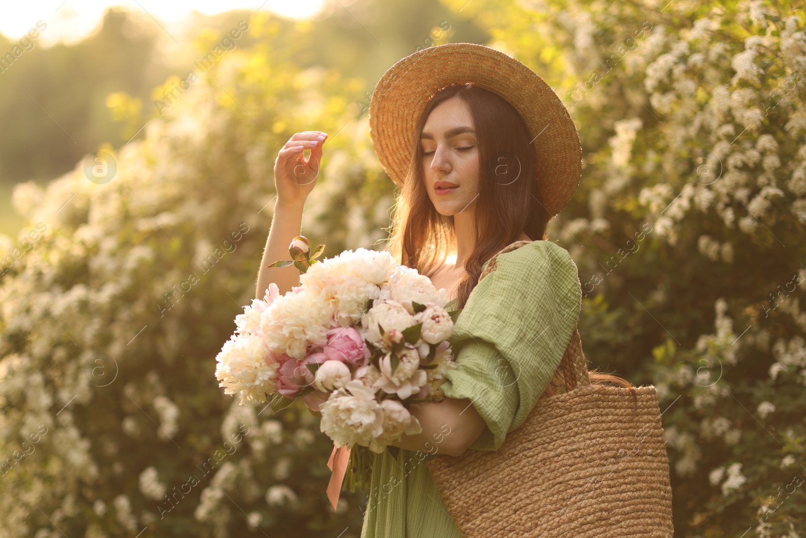 Beautiful woman with bouquet of peonies in park on sunny day Photo of Beautiful woman with bouquet of peonies in park on sunny day