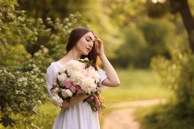 Photo of Beautiful woman with bouquet of peonies in park. Space for text