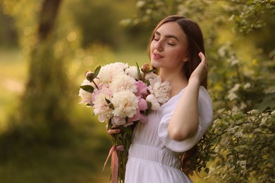 Photo of Beautiful woman with bouquet of peonies in park