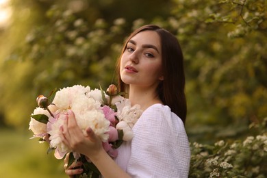 Photo of Beautiful woman with bouquet of peonies in park