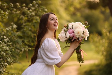 Photo of Beautiful woman with bouquet of peonies in park