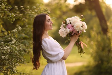 Photo of Beautiful woman with bouquet of peonies in park