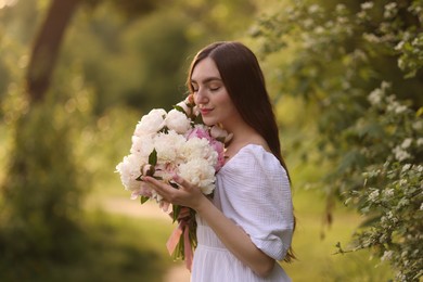 Photo of Beautiful woman with bouquet of peonies in park