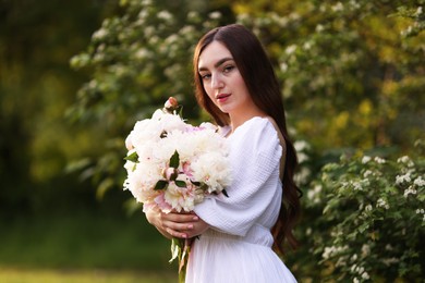 Photo of Beautiful woman with bouquet of peonies in park