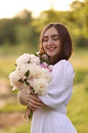 Photo of Beautiful woman with bouquet of peonies in park on sunny day