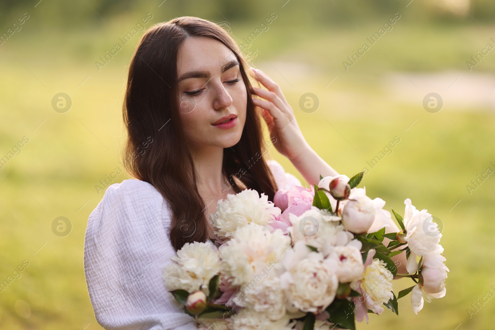 Photo of Beautiful woman with bouquet of peonies in park
