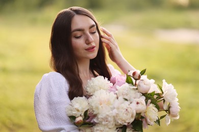 Photo of Beautiful woman with bouquet of peonies in park