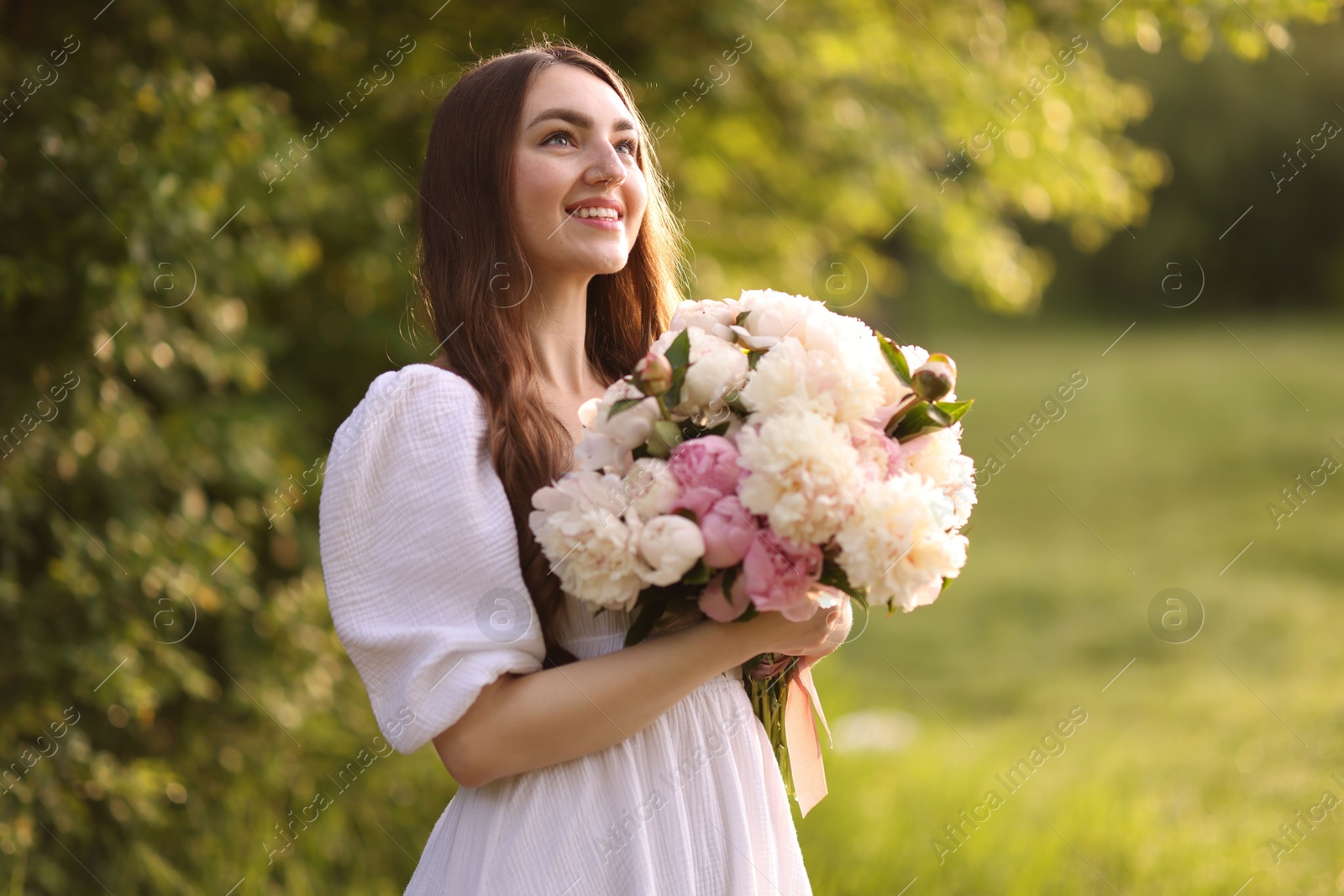 Beautiful woman with bouquet of peonies in park Photo of Beautiful woman with bouquet of peonies in park