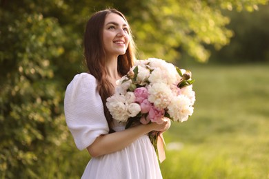 Photo of Beautiful woman with bouquet of peonies in park