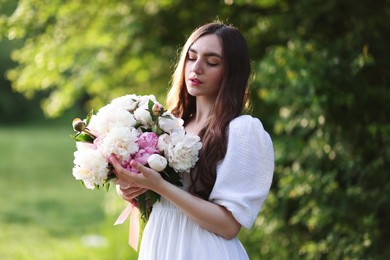 Photo of Beautiful woman with bouquet of peonies in park