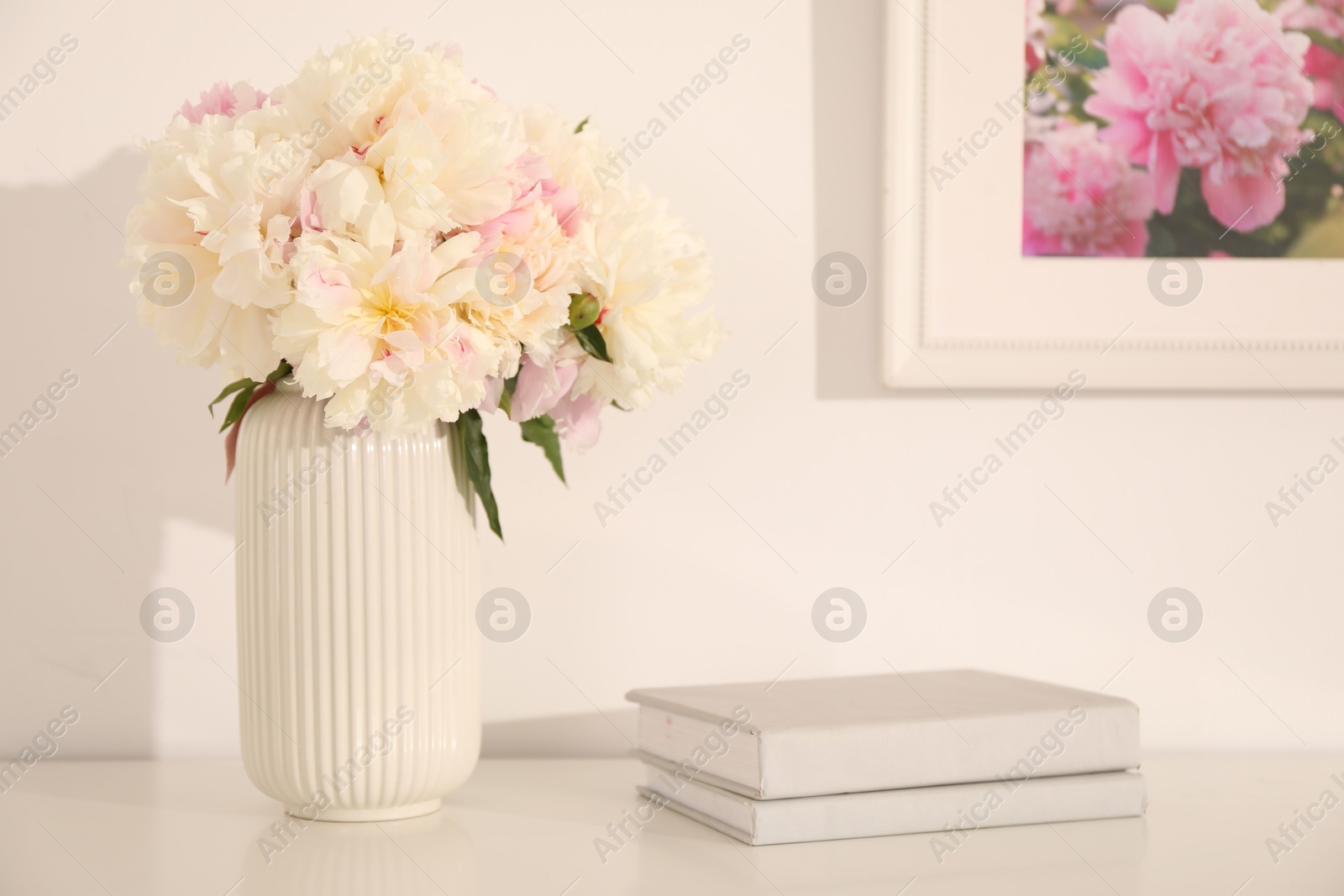 Bouquet of beautiful peonies and books on table indoors Photo of Bouquet of beautiful peonies and books on table indoors