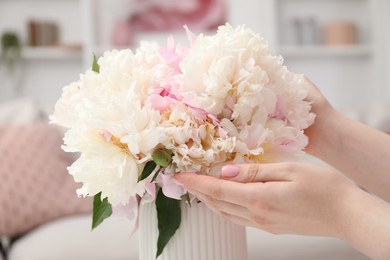 Photo of Woman with bouquet of beautiful peonies at home, closeup