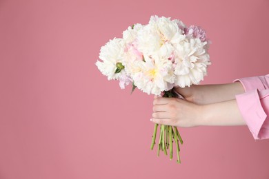 Photo of Woman with bouquet of beautiful peonies on pink background, closeup. Space for text