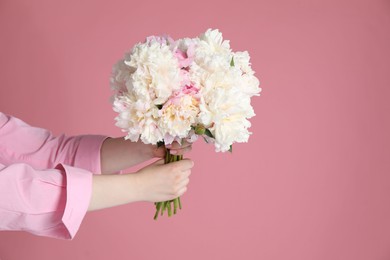 Photo of Woman with bouquet of beautiful peonies on pink background, closeup. Space for text