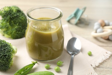 Photo of Baby food. Tasty puree in glass jar, ingredients and spoon on table, closeup