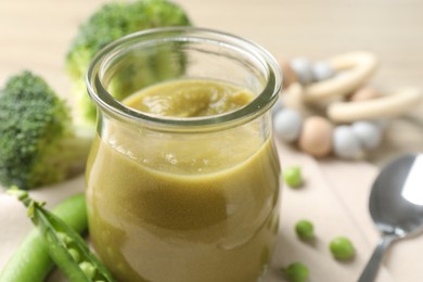 Photo of Baby food. Tasty puree in glass jar and ingredients on table, closeup