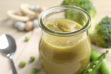 Photo of Baby food. Tasty puree in glass jar and ingredients on table, closeup