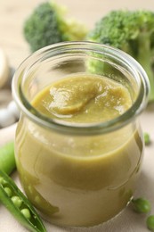 Photo of Baby food. Tasty puree in glass jar and ingredients on table, closeup