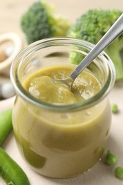 Photo of Baby food. Tasty puree in glass jar and ingredients on table, closeup