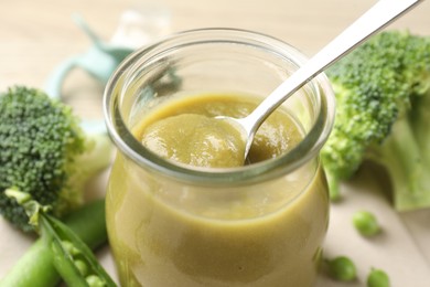 Photo of Baby food. Tasty puree in glass jar and ingredients on table, closeup